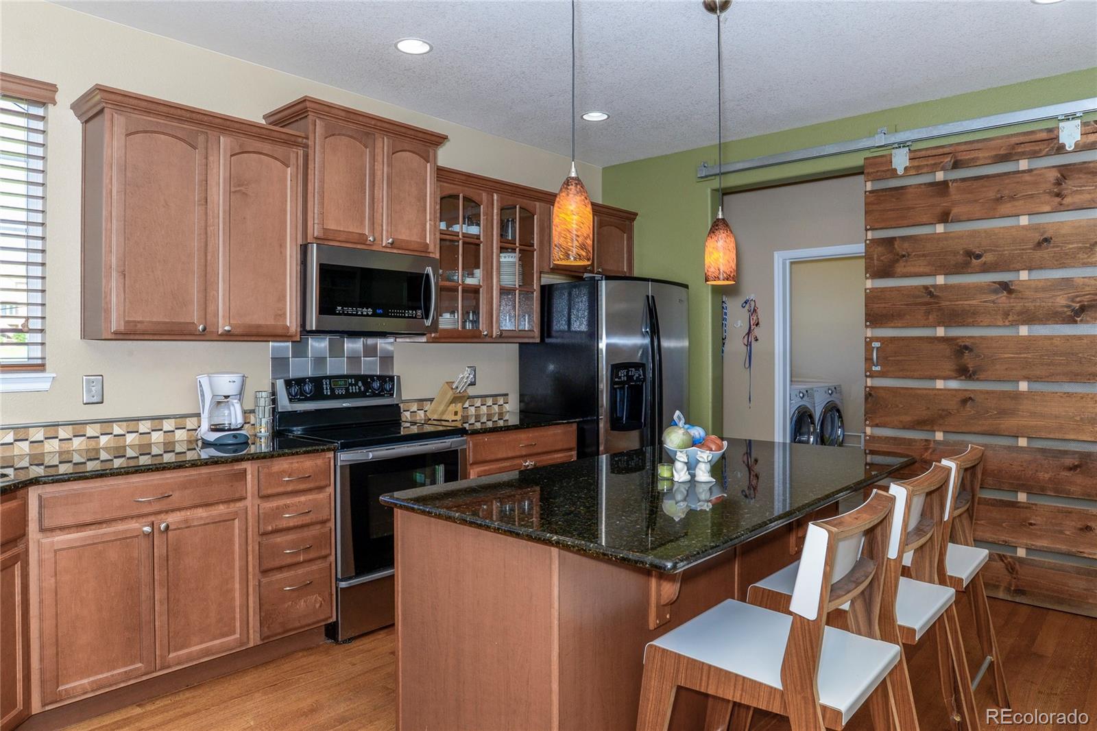 10926 Towerbridge Road Highlands Ranch, CO 80130 - Photo 10 of 34 a kitchen with stainless steel appliances granite countertop a stove refrigerator and microwave