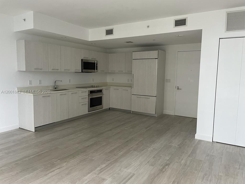 55 Southwest 9th Street, Unit 3102 Miami, FL 33130 - Photo 3 of 13 a view of a kitchen with a sink and a refrigerator