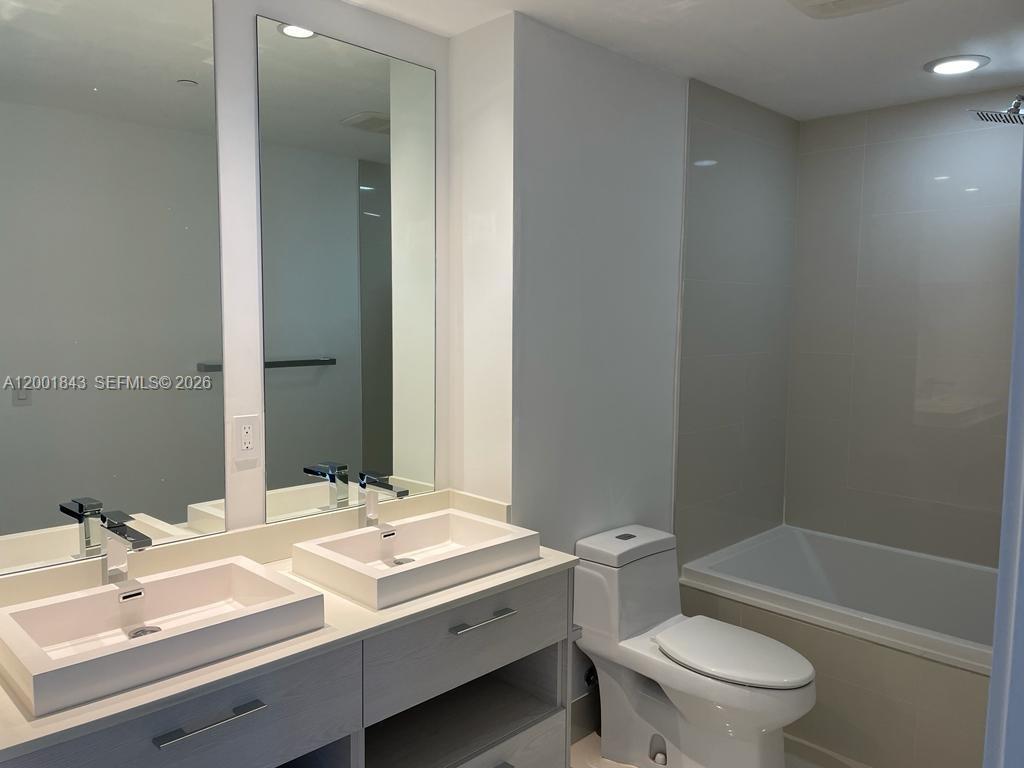 55 Southwest 9th Street, Unit 3102 Miami, FL 33130 - Photo 6 of 13 a bathroom with a double vanity sink toilet and shower