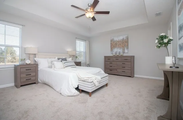 a spacious bedroom with a bed a dresser and a chandelier