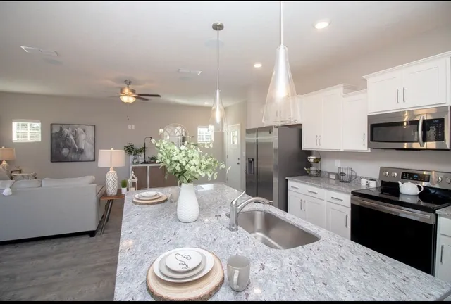 a kitchen with stainless steel appliances granite countertop a refrigerator a stove a sink dishwasher and white cabinets with wooden floor