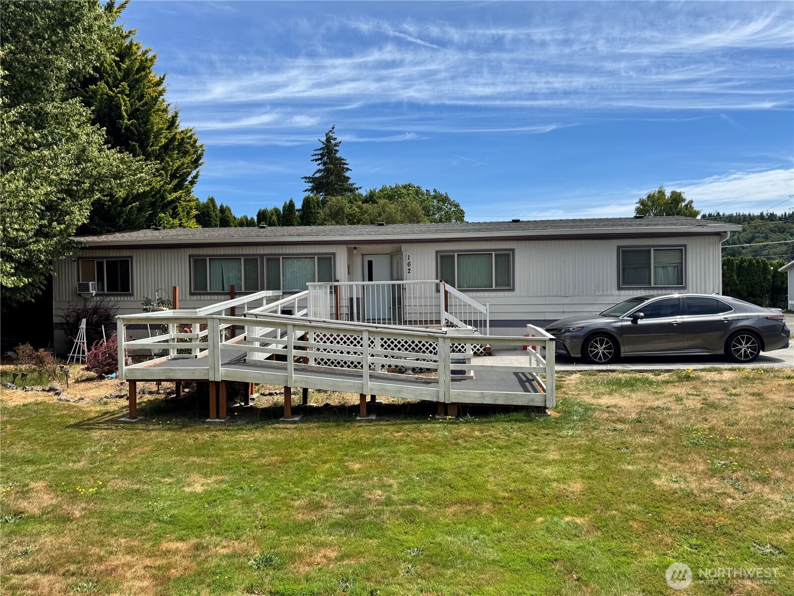 a front view of a house with a garden and car parked