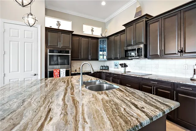 a kitchen with granite countertop a sink a counter top space appliances and cabinets