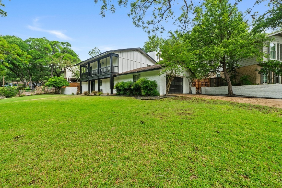 a view of a house next to a big yard and large trees