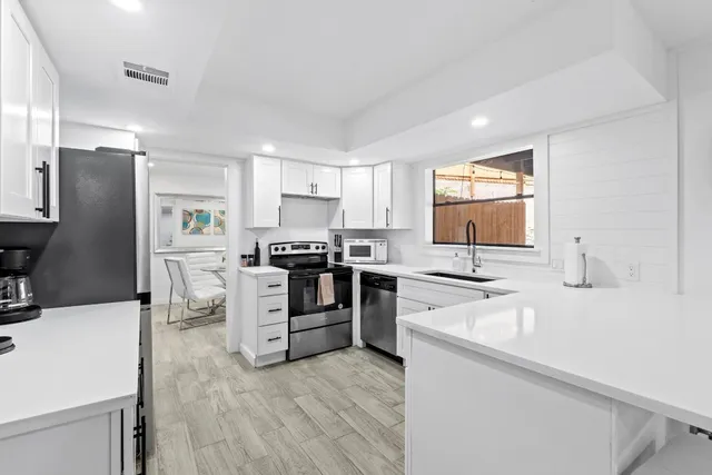 a kitchen with white cabinets and stainless steel appliances