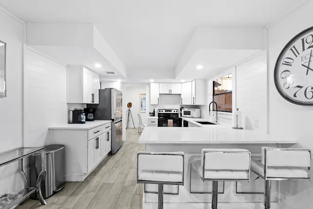 a large white kitchen with lots of counter space and stainless steel appliances