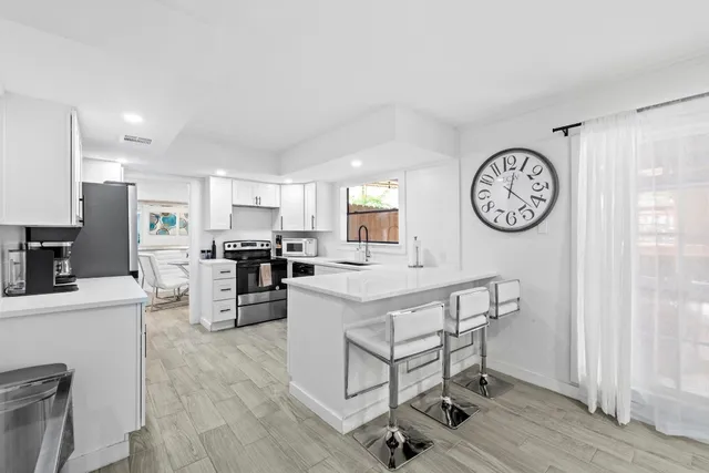 a kitchen with a table chairs and a clock on the wall