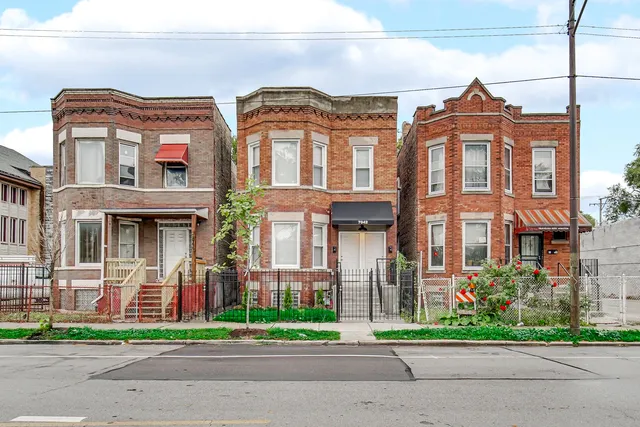 a front view of a residential apartment building with a yard and plants