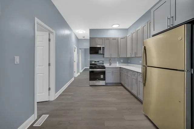 a kitchen with a refrigerator a stove top oven and cabinets