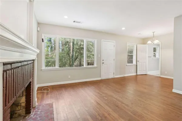 a view of an empty room with wooden floor and a window