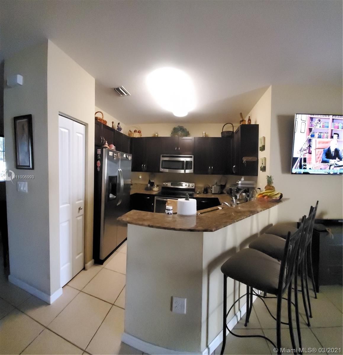 14140 Southwest 275th Street, Unit 1 Homestead, FL 33032 - Photo 5 of 25 a kitchen with kitchen island a refrigerator and a stove top oven