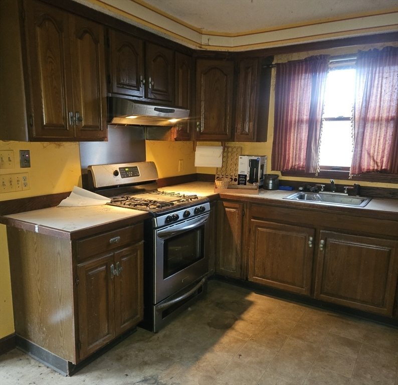 664 Norman Street Fall River, MA 02721 - Photo 9 of 12 a kitchen with granite countertop a stove top oven sink and cabinets