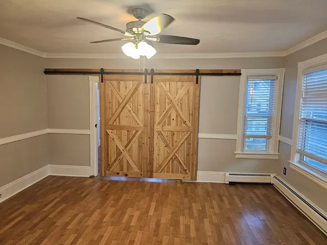 an empty room with wooden floor fan and windows