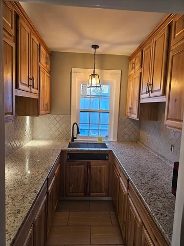 a kitchen with kitchen island granite countertop a sink stove and cabinets
