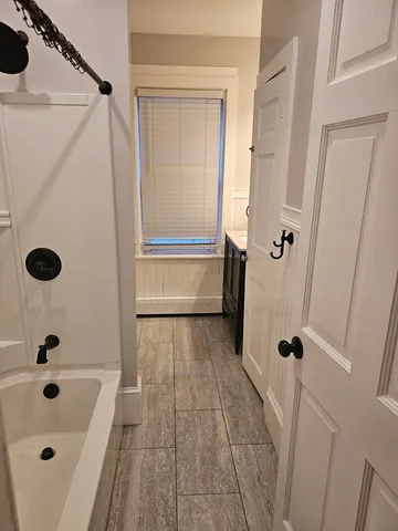 a bathroom with a tub a sink a window and shower