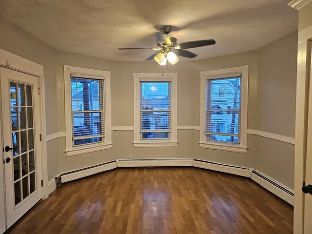 a view of an empty room with wooden floor and a window
