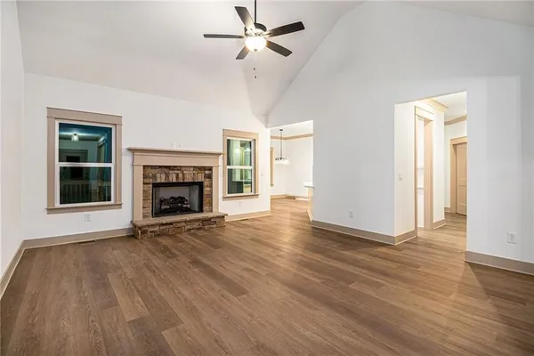 an empty room with wooden floor fireplace and windows