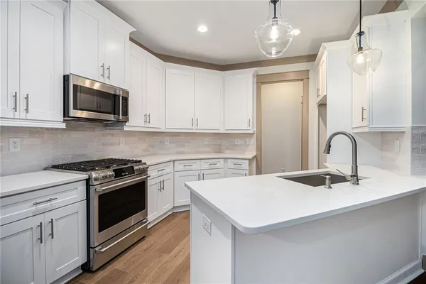 a kitchen with granite countertop a sink stainless steel appliances and white cabinets