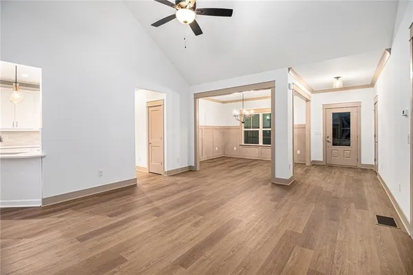 an empty room with wooden floor fan and windows