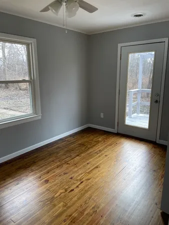 an empty room with wooden floor and windows