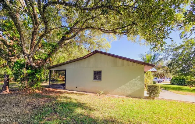 a view of yellow house with a yard and large tree