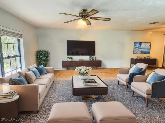 a living room with furniture a flat screen tv and a window