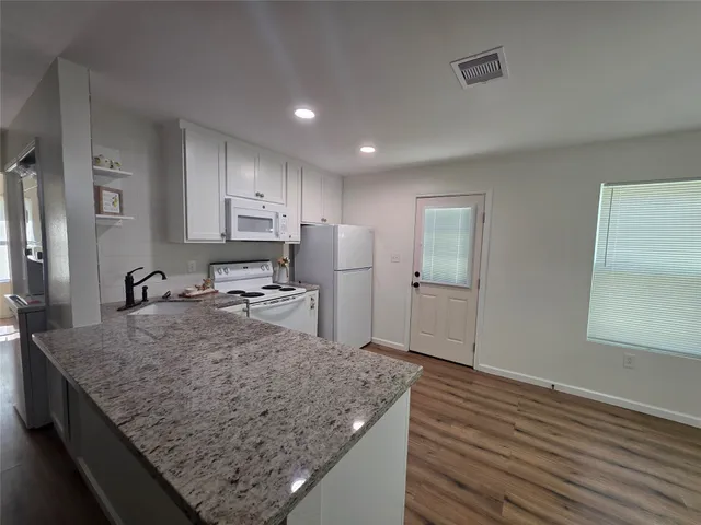 a kitchen with stainless steel appliances granite countertop a sink refrigerator and cabinets