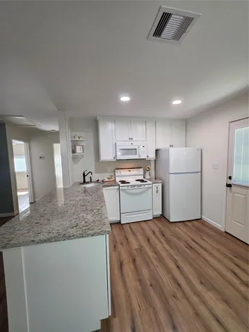 a kitchen with a refrigerator a sink and dishwasher with wooden floor