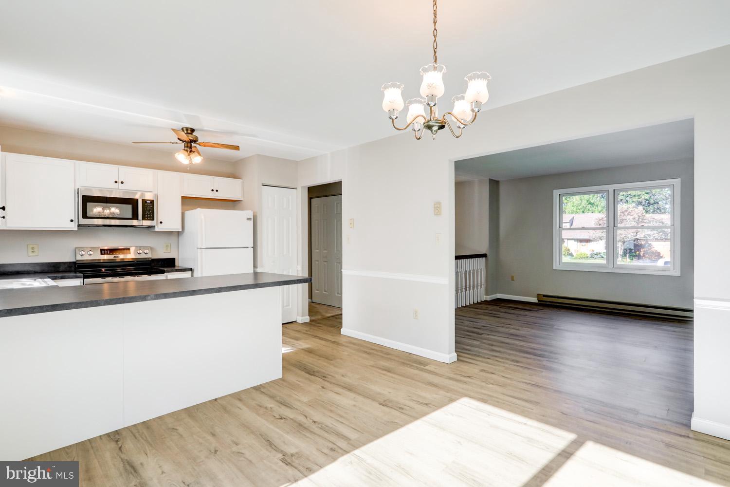 230 Hickory Drive Lititz, PA 17543 - Photo 20 of 43 a large white kitchen with kitchen island a chandelier wooden floor and a view of living room