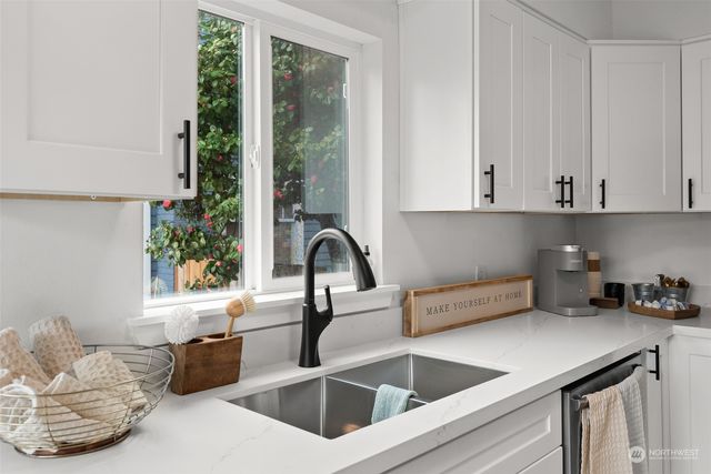 a kitchen with stainless steel appliances granite countertop a sink a counter space and a window