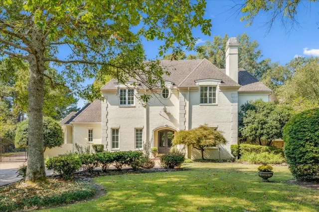 a view of a white house with a big yard and potted plants
