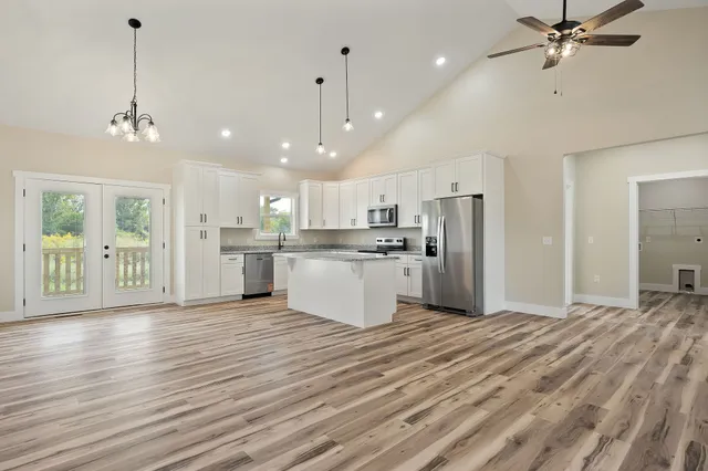 a view of a kitchen with a refrigerator a kitchen island a stove and wooden floor
