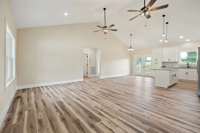 an empty room with wooden floor an entryway and windows
