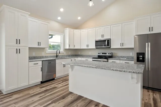 a kitchen with granite countertop white cabinets and stainless steel appliances