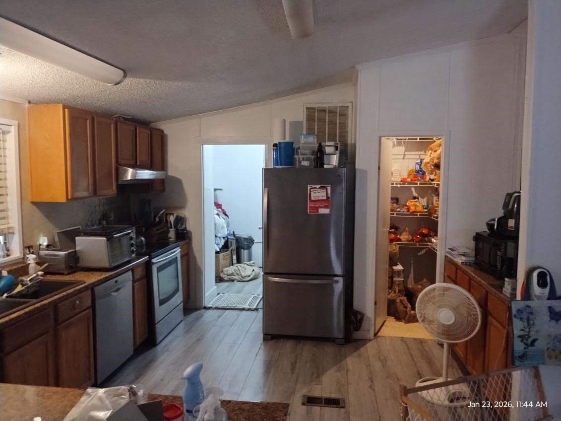 180 Woods Road Coldspring, TX 77331 - Photo 7 of 35 a kitchen with a refrigerator and a stove top oven