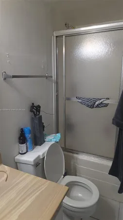 a bathroom with a granite countertop bathtub sink vanity mirror and toilet