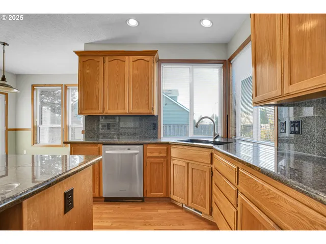 a kitchen with stainless steel appliances granite countertop a sink and a refrigerator