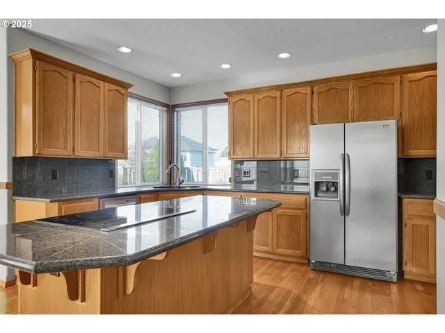 a kitchen with stainless steel appliances kitchen island granite countertop a refrigerator a stove top oven and white cabinets