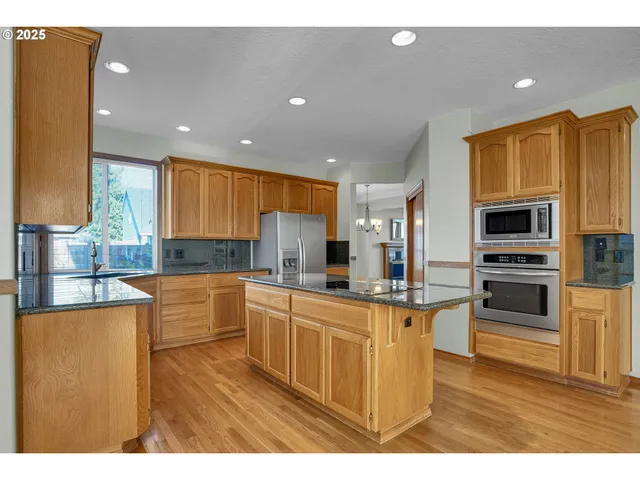 a kitchen with stainless steel appliances granite countertop a sink refrigerator and cabinets