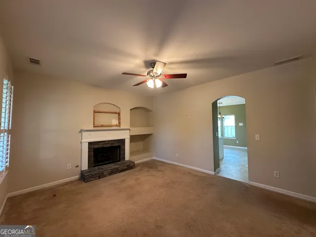 a view of an empty room with a fireplace and a fan