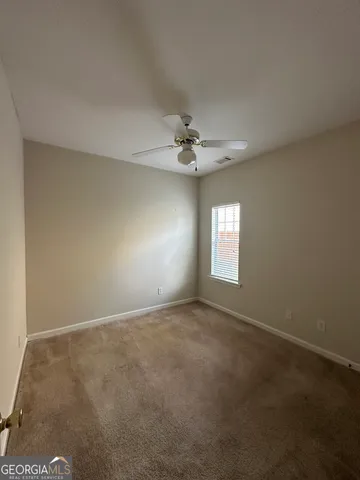 an empty room with a window and a ceiling fan