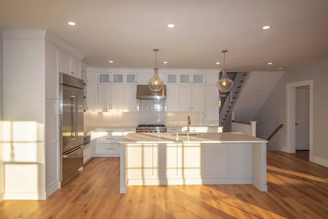 a kitchen with a stove a refrigerator and a dining table with wooden floor