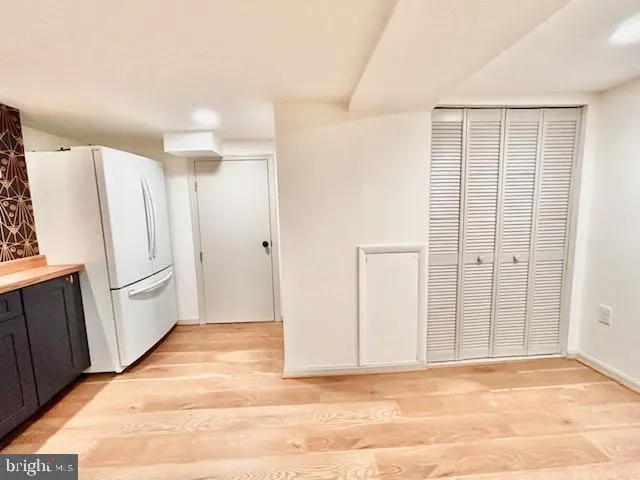 a view of a kitchen with refrigerator and white wall