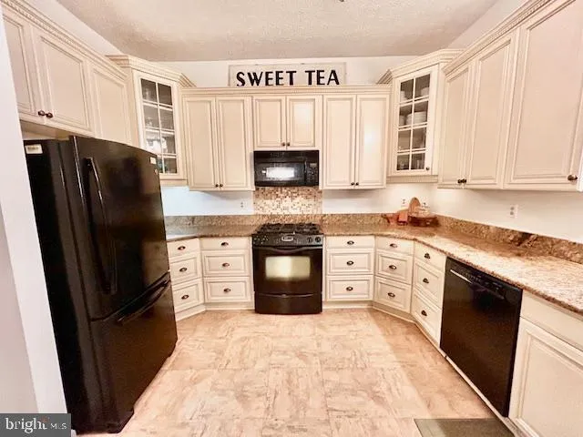 a kitchen with granite countertop a refrigerator stove and sink