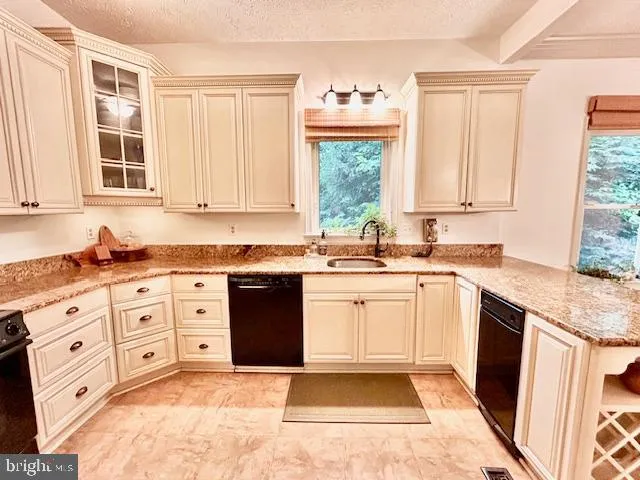 a kitchen with granite countertop a sink window and cabinets