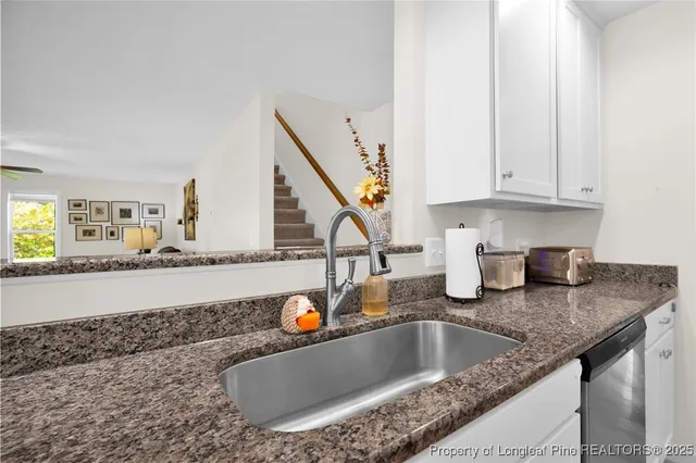 a kitchen with granite countertop a sink and a white wooden cabinets