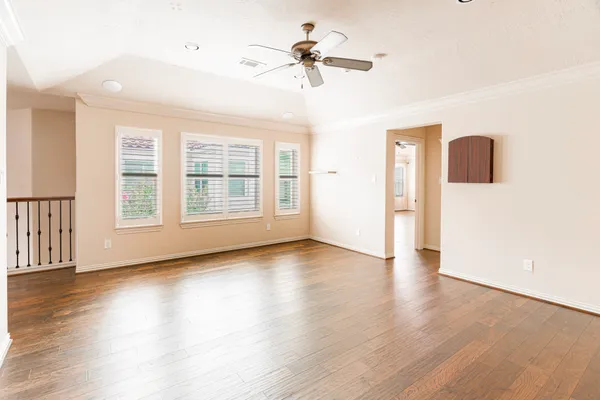 a view of an empty room with wooden floor and a window