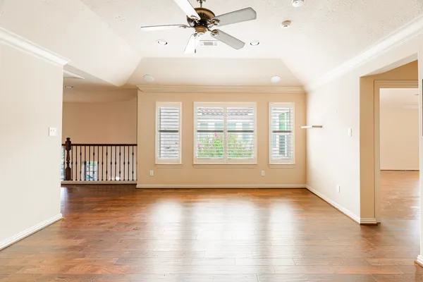 a view of an empty room with a window and wooden floor