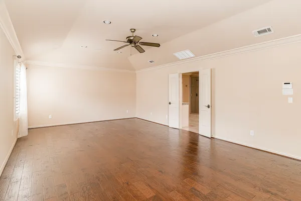 an empty room with wooden floor closet and fan