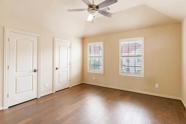 a view of an empty room with wooden floor and window